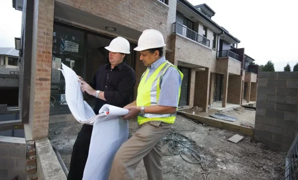 Two architects checking blueprint while in the construction site