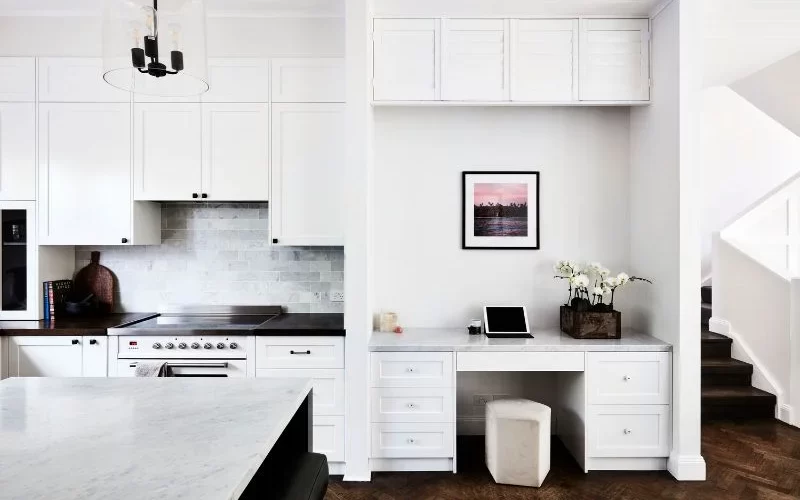 Interior photography of a fresh white kitchen and home office area with stairs on the right