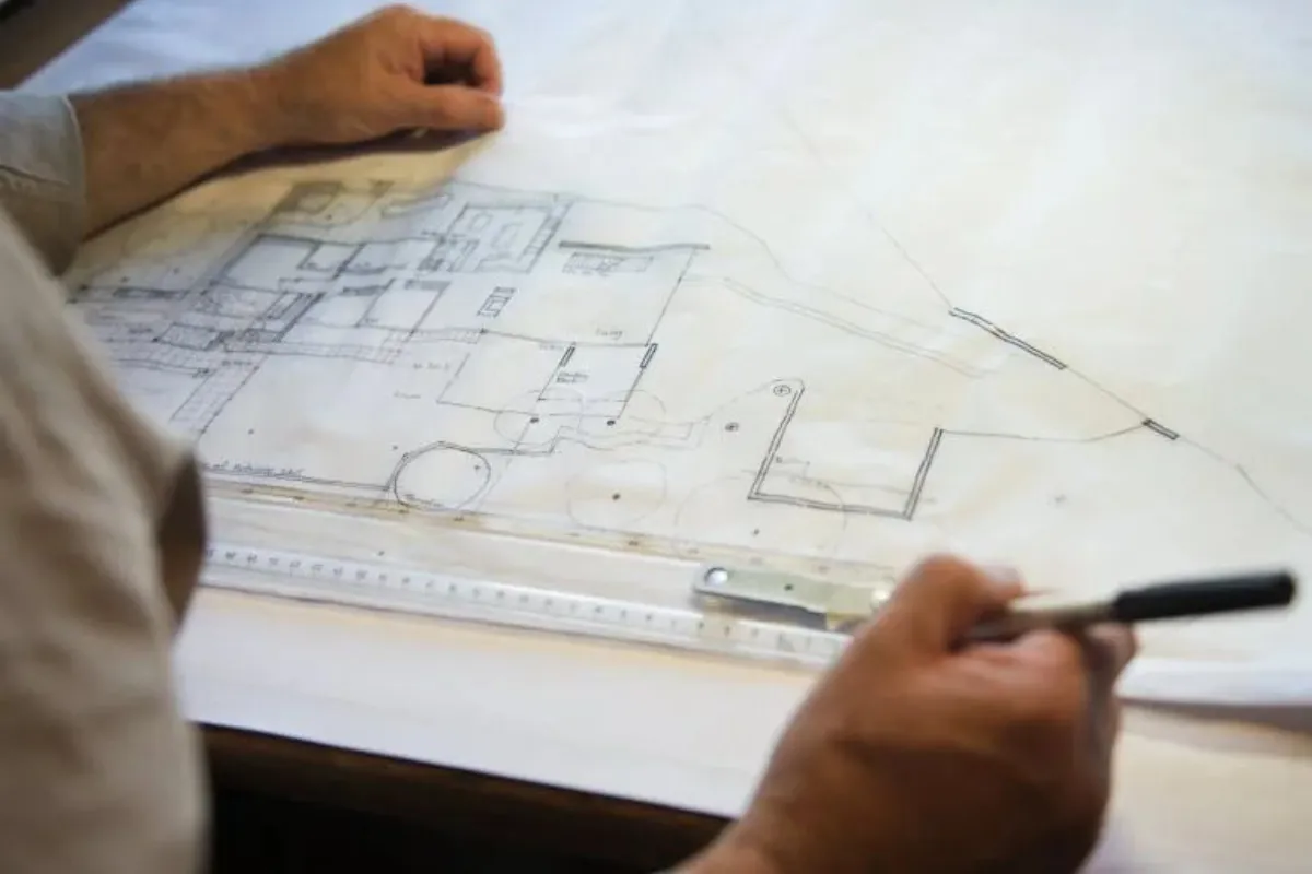 Person reviewing architectural plans and measurements for a residential building design project.