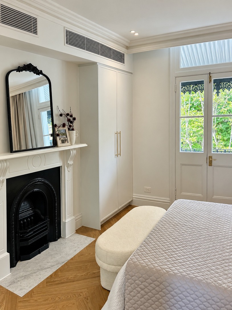 Bedroom with fireplace, arched mirror and built-in wardrobe in a Paddington heritage terrace