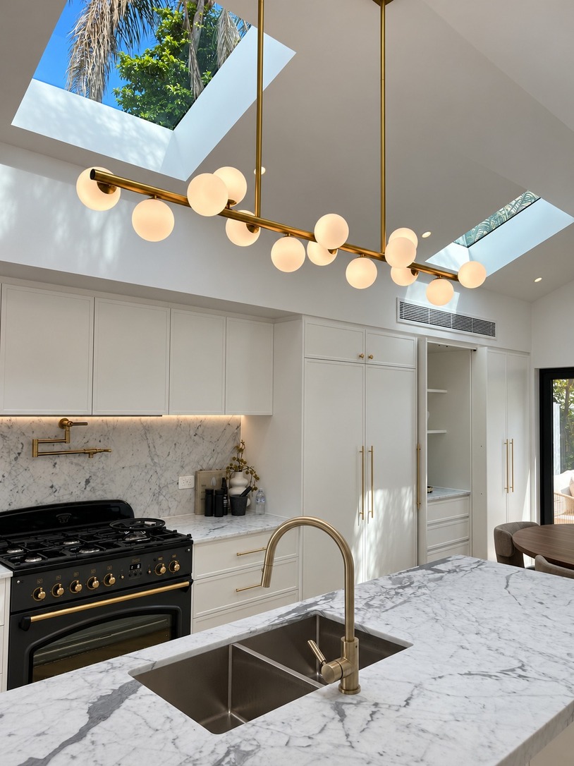 Kitchen with skylights, globe pendant and marble island bench in a narrow Paddington terrace